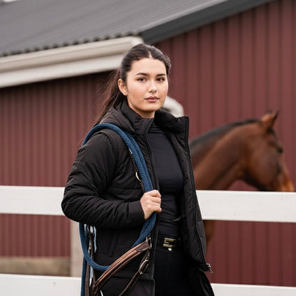 Woman holding a horse bridle in front of a barn