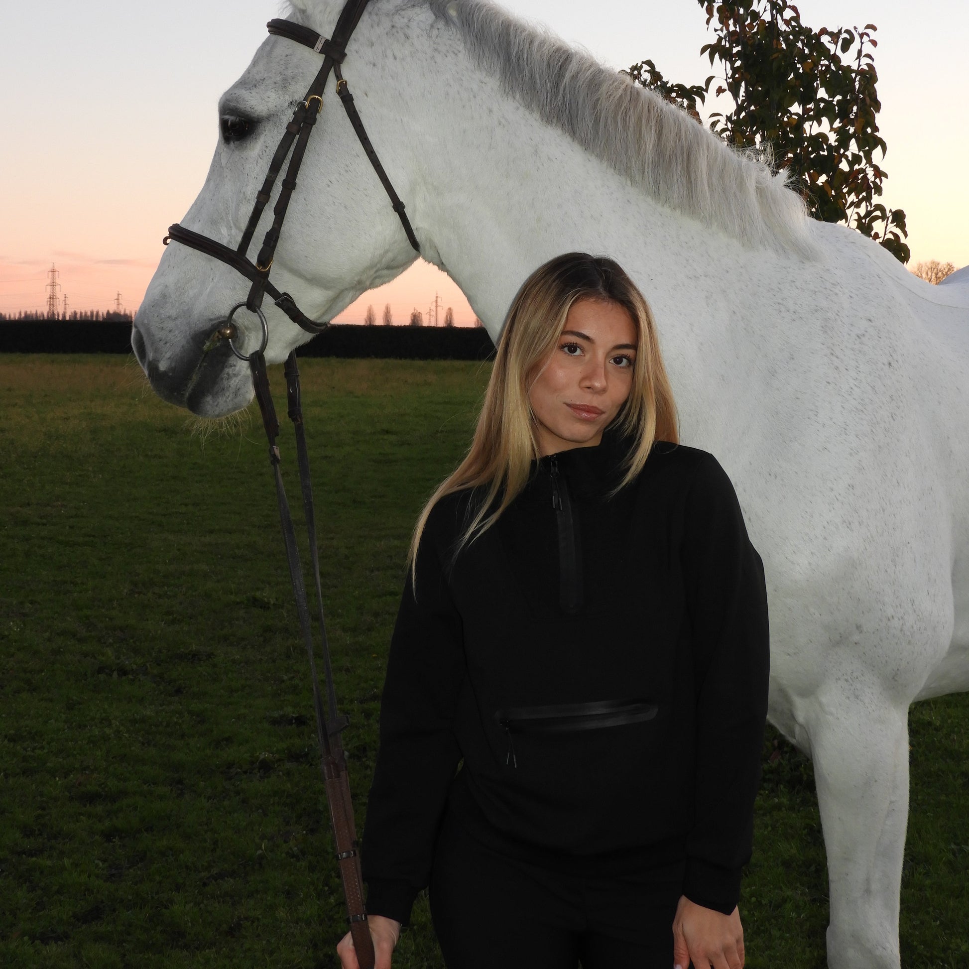Woman standing next to a white horse on a grassy field
