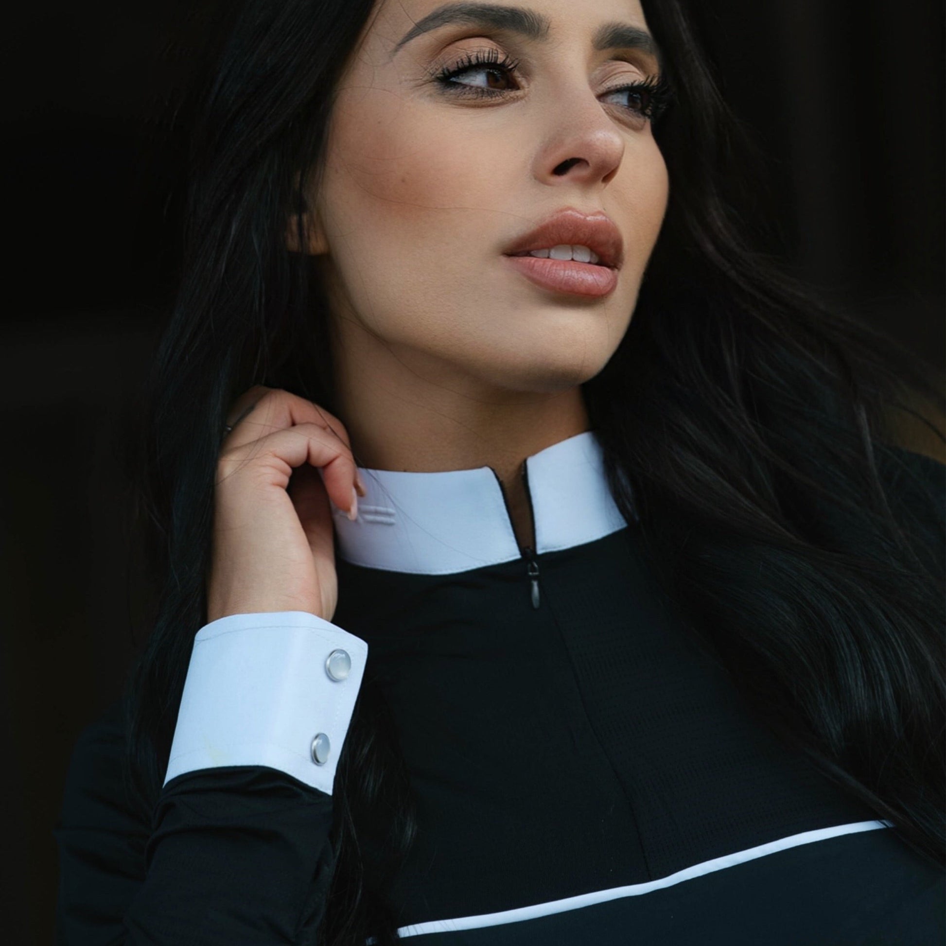 Woman wearing a black outfit with white accents against a dark background